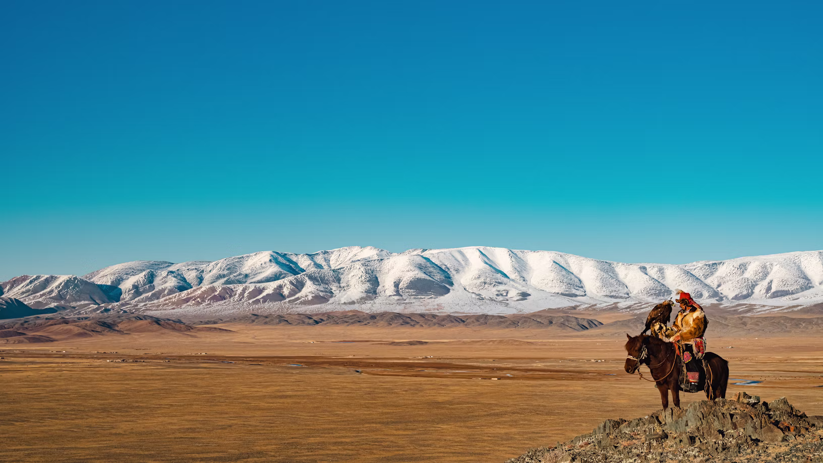A lone rider crossing the open Mongolian steppe at golden hour